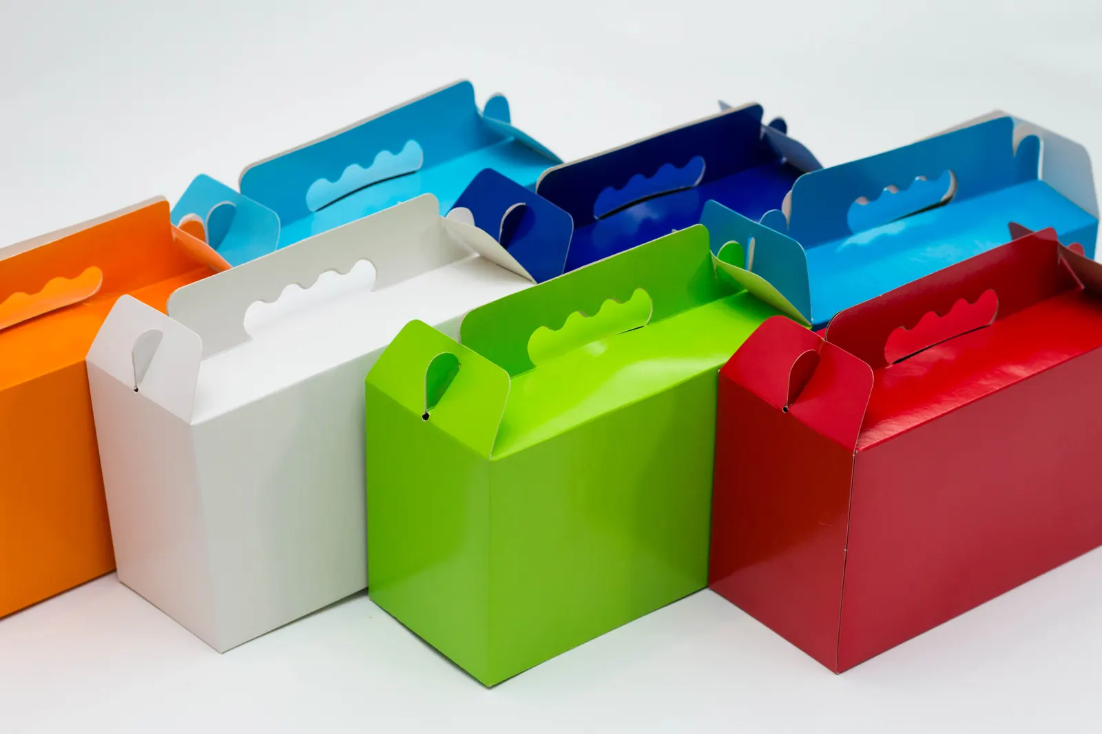 Cajas de cartón plegadizo con asa en naranja, blanco, verde, rojo y azul
